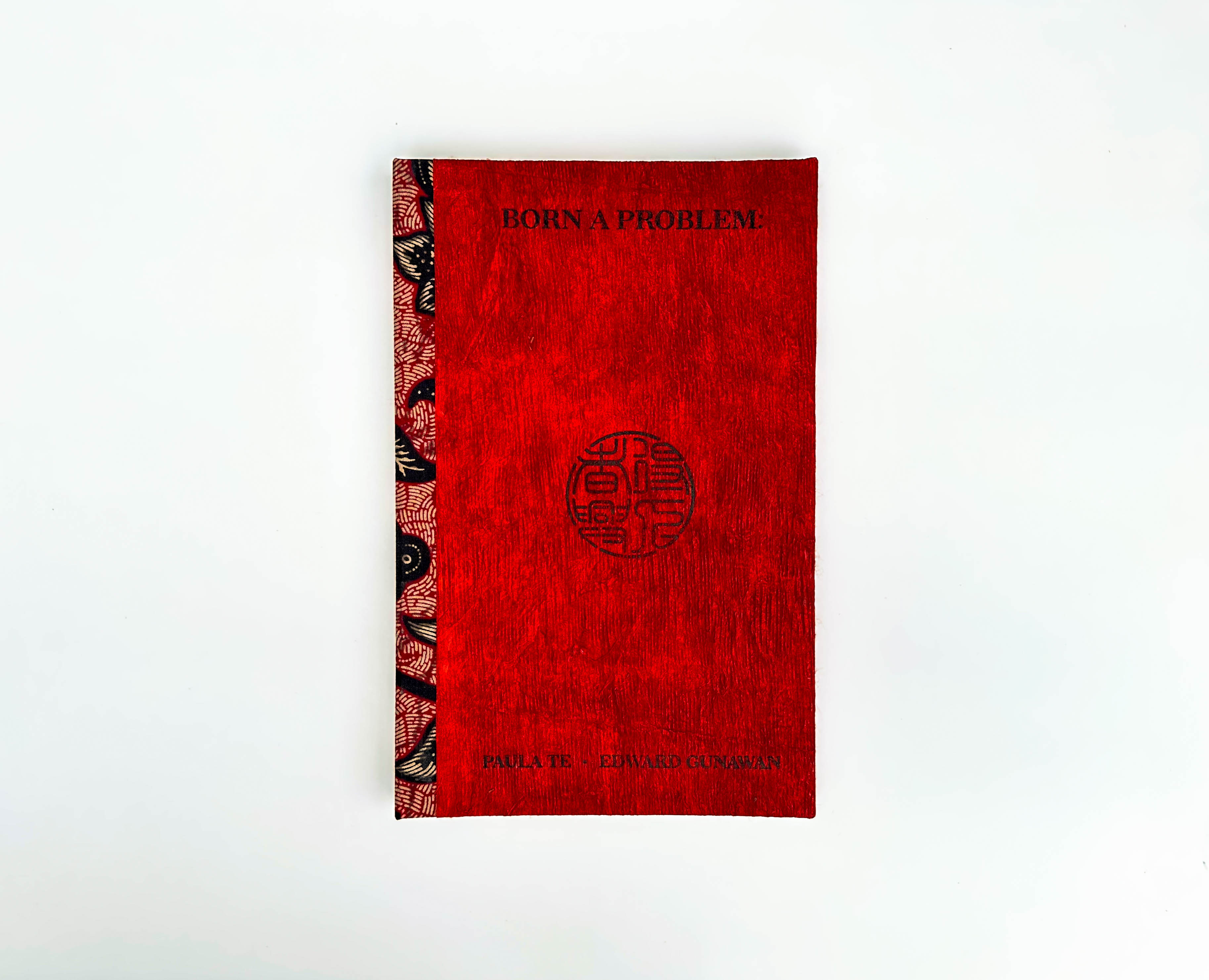 The cover of Born A Problem, red book with black stamped text and seal