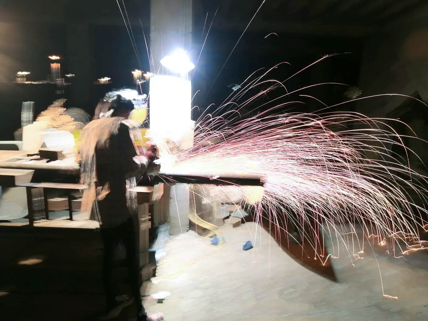 A photo of Paula welding an animal enrichment structure, sparks flying